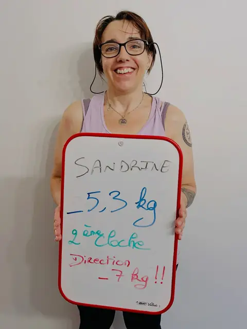 Une ardoise blanche, un bilan écrit dessus, une membre qui le présente depuis la salle du club
